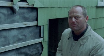 Movie still from “Insomnia” (1997), directed by Erik Skjoldbjærg – A man standing in front of a green building; Close Up shot, Low angle