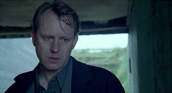 Movie still from “Insomnia” (1997), directed by Erik Skjoldbjærg – A person wearing a suit and tie; Close Up shot, Low angle