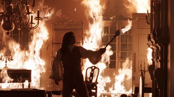 Movie still from “Interview with the Vampire: The Vampire Chronicles” (1994), directed by Neil Jordan – A man holding a guitar in front of a fire; Medium shot, Low angle