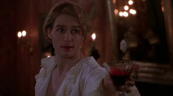 Movie still from “Interview with the Vampire: The Vampire Chronicles” (1994), directed by Neil Jordan – A woman holding a glass of red wine in her right hand; Close Up shot, Over the shoulder angle