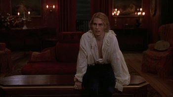 Movie still from “Interview with the Vampire: The Vampire Chronicles” (1994), directed by Neil Jordan – A man standing in front of a couch in a living room; Medium shot, Over the shoulder angle