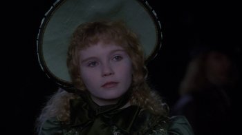 Movie still from “Interview with the Vampire: The Vampire Chronicles” (1994), directed by Neil Jordan – A young girl wearing a green dress and a green hat; Close Up shot, Over the shoulder angle
