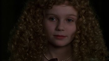 Movie still from “Interview with the Vampire: The Vampire Chronicles” (1994), directed by Neil Jordan – A young girl with long curly hair wearing a necklace; Close Up shot, High angle