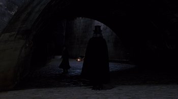 Movie still from “Interview with the Vampire: The Vampire Chronicles” (1994), directed by Neil Jordan – A man in a top hat standing in the dark; Wide shot, Over the shoulder angle