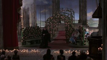 Movie still from “Interview with the Vampire: The Vampire Chronicles” (1994), directed by Neil Jordan – A woman in a black dress sitting in front of candles; Extreme Wide shot, High angle