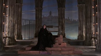Movie still from “Interview with the Vampire: The Vampire Chronicles” (1994), directed by Neil Jordan – A woman sitting on steps in front of a painting; Wide shot, High angle