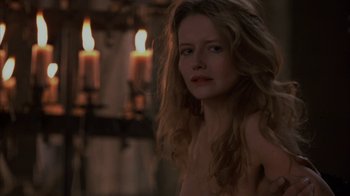 Movie still from “Interview with the Vampire: The Vampire Chronicles” (1994), directed by Neil Jordan – A woman with long blonde hair standing in front of candles in a room; Close Up shot, Over the shoulder angle
