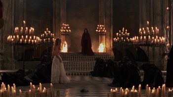 Movie still from “Interview with the Vampire: The Vampire Chronicles” (1994), directed by Neil Jordan – A woman in a white dress sitting in front of candles; Wide shot, High angle