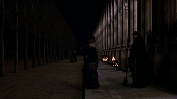 Movie still from “Interview with the Vampire: The Vampire Chronicles” (1994), directed by Neil Jordan – A woman standing on the side of a road near a fire pit at night; Wide shot, High angle