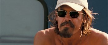 Movie still from “Into the Blue” (2005), directed by John Stockwell – A person wearing a hat and sunglasses; Close Up shot, Over the shoulder angle