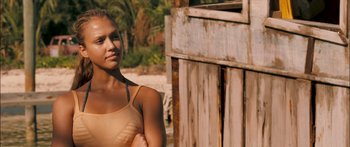 Movie still from “Into the Blue” (2005), directed by John Stockwell – A beautiful young woman standing next to a wooden building; Close Up shot, Over the shoulder angle