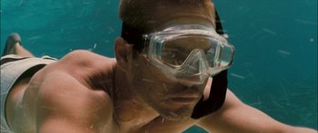 Movie still from “Into the Blue” (2005), directed by John Stockwell – A person wearing goggles in the water; Close Up shot, Overhead angle