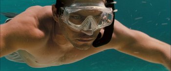 Movie still from “Into the Blue” (2005), directed by John Stockwell – A man swimming underwater wearing goggles and a mask; Close Up shot, High angle