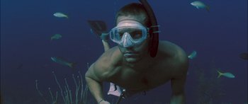 Movie still from “Into the Blue” (2005), directed by John Stockwell – A man swimming underwater wearing a mask and flippers; Medium shot, Low angle
