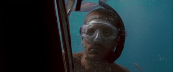 Movie still from “Into the Blue” (2005), directed by John Stockwell – A man wearing a mask and goggles in the water; Close Up shot, Low angle