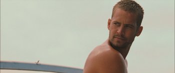 Movie still from “Into the Blue” (2005), directed by John Stockwell – A man with no shirt is posing for a picture; Close Up shot, Over the shoulder angle