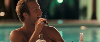 Movie still from “Into the Blue” (2005), directed by John Stockwell – A man smoking a cigar in front of a swimming pool; Close Up shot, Over the shoulder angle