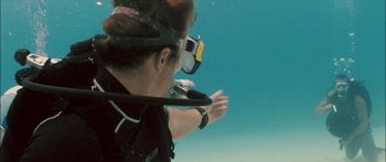 Movie still from “Into the Blue” (2005), directed by John Stockwell – A man in a scuba suit is swimming underwater; Wide shot, High angle