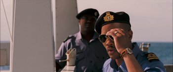 Movie still from “Into the Blue” (2005), directed by John Stockwell – A man in a police uniform is looking over his sunglasses; Close Up shot, Low angle