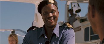 Movie still from “Into the Blue” (2005), directed by John Stockwell – A man in a uniform smiles for the camera; Close Up shot, Low angle