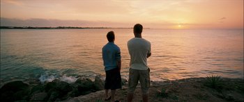 Movie still from “Into the Blue” (2005), directed by John Stockwell – Two young men standing on the shore watching the sunset; Wide shot, Low angle