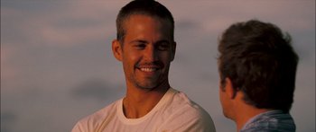 Movie still from “Into the Blue” (2005), directed by John Stockwell – A person wearing a white t - shirt smiling; Close Up shot, Over the shoulder angle