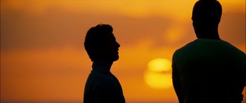 Movie still from “Into the Blue” (2005), directed by John Stockwell – A man standing in front of the setting sun; Wide shot, Over the shoulder angle
