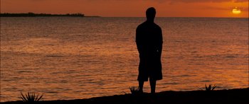 Movie still from “Into the Blue” (2005), directed by John Stockwell – A man standing on the beach looking out at the water; Extreme Wide shot, High angle
