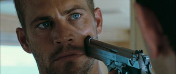 Movie still from “Into the Blue” (2005), directed by John Stockwell – A person holding a gun up to their face; Close Up shot, Over the shoulder angle
