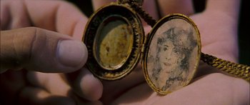Movie still from “Into the Blue” (2005), directed by John Stockwell – A person holding an old picture of a woman in an antique locket; Extreme Close Up shot, Overhead angle