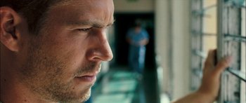Movie still from “Into the Blue” (2005), directed by John Stockwell – A man's face as a man walks by in the background; Close Up shot, Over the shoulder angle