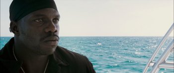 Movie still from “Into the Blue” (2005), directed by John Stockwell – A man standing in front of a body of water; Close Up shot, Over the shoulder angle