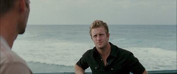 Movie still from “Into the Blue” (2005), directed by John Stockwell – A person sitting on a ledge near the ocean; Close Up shot, Over the shoulder angle