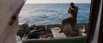 Movie still from “Into the Blue” (2005), directed by John Stockwell – A man sitting on the back of a boat in the water; Wide shot, High angle