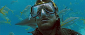 Movie still from “Into the Blue” (2005), directed by John Stockwell – A man wearing a diving suit and goggles in the ocean; Close Up shot, Low angle