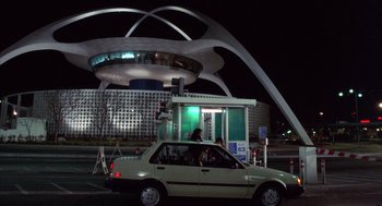 Movie still from “Into the Night” (1985), directed by John Landis – A car parked in front of a building at night; Extreme Wide shot, Low angle