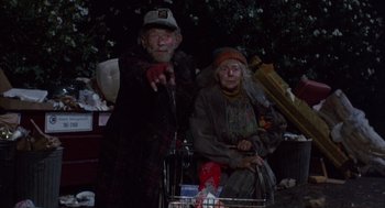 Movie still from “Into the Night” (1985), directed by John Landis – An older man standing next to an older woman; Medium shot, Low angle