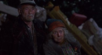 Movie still from “Into the Night” (1985), directed by John Landis – An older man and woman sitting next to each other; Close Up shot, High angle