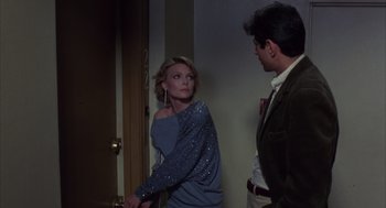 Movie still from “Into the Night” (1985), directed by John Landis – A man and a woman standing next to each other in front of a door; Medium shot, Over the shoulder angle
