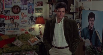 Movie still from “Into the Night” (1985), directed by John Landis – A man standing in front of a living room wall; Medium shot, Over the shoulder angle