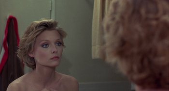 Movie still from “Into the Night” (1985), directed by John Landis – A woman looking in the mirror in front of a bathroom mirror; Close Up shot, Over the shoulder angle