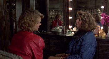 Movie still from “Into the Night” (1985), directed by John Landis – Two women sitting in front of each other in front of a mirror; Medium shot, Over the shoulder angle