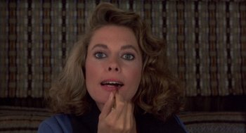Movie still from “Into the Night” (1985), directed by John Landis – A person holding their finger to her mouth; Close Up shot, Over the shoulder angle
