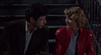 Movie still from “Into the Night” (1985), directed by John Landis – A man and a woman sitting next to each other on steps; Medium shot, Over the shoulder angle