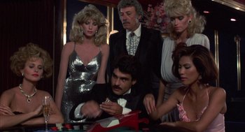 Movie still from “Into the Night” (1985), directed by John Landis – A group of men and women sitting around a table; Medium shot, High angle