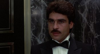 Movie still from “Into the Night” (1985), directed by John Landis – A person wearing a suit and a bow tie; Close Up shot, Low angle