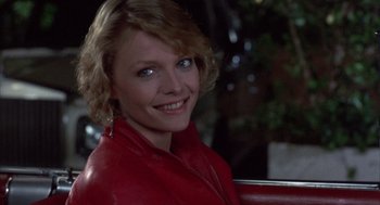 Movie still from “Into the Night” (1985), directed by John Landis – A woman in a red jacket sitting on a bench; Close Up shot, Low angle