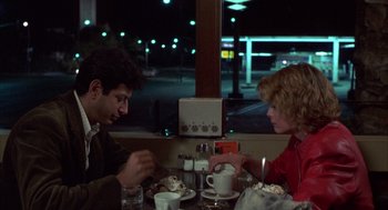 Movie still from “Into the Night” (1985), directed by John Landis – A man and a woman sitting at a dinner table; Medium shot, Over the shoulder angle