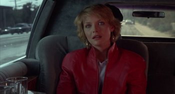 Movie still from “Into the Night” (1985), directed by John Landis – A woman sitting in the back seat of a car; Close Up shot, Over the shoulder angle