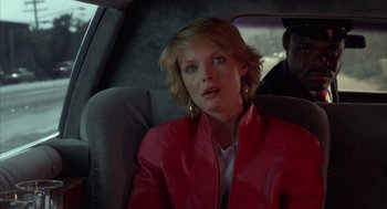 Movie still from “Into the Night” (1985), directed by John Landis – A woman sitting in the back seat of a car; Close Up shot, Over the shoulder angle